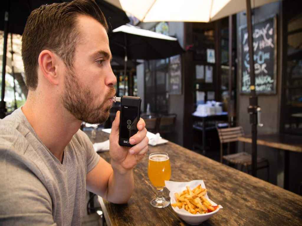Man blowing to a breathalyser before eating and drinking