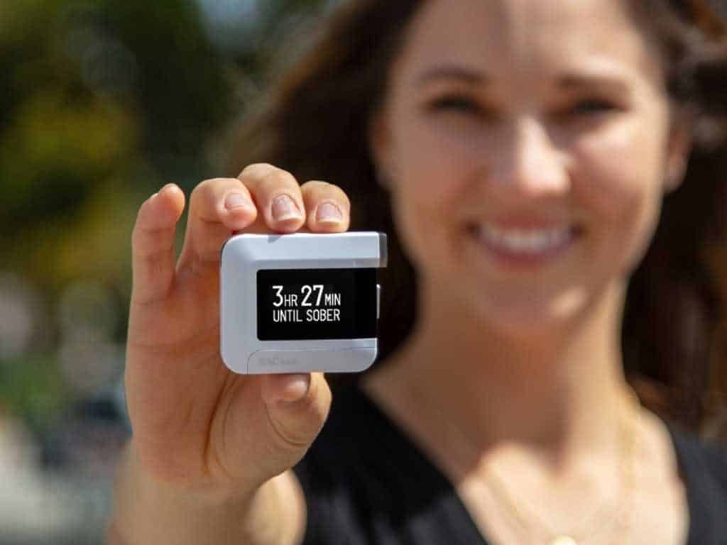 Woman holding a BACtrack breathalyzer showing how long sobriety will return