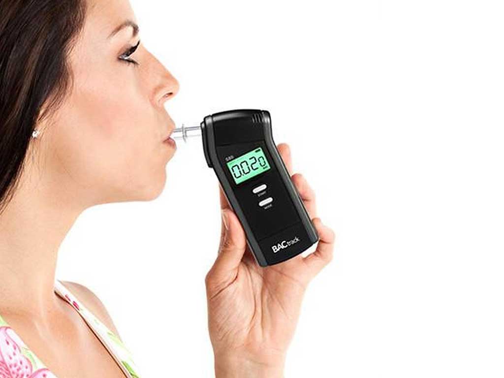 A woman using a personal breathalyser