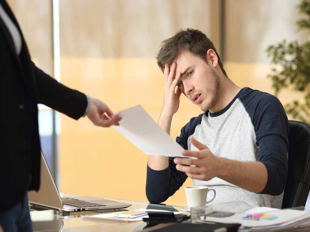 Employer handing over a paper to an anxious male individual
