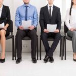 Four job applicants sitting while holding their resume