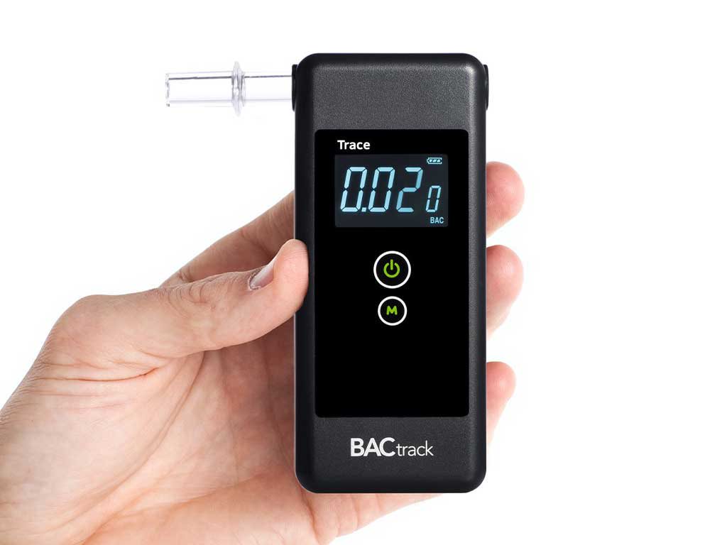 Hand holding a breathalyser showing the BAC result