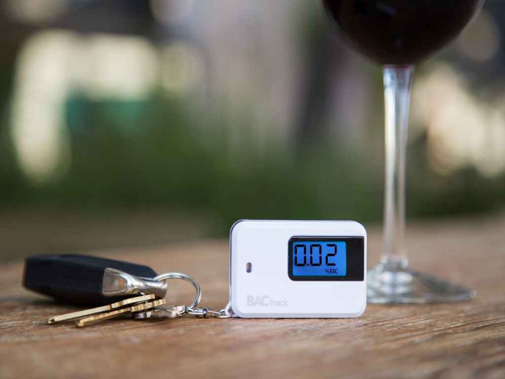 A breathalyser, car key and wine glass on the table.