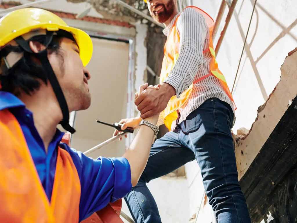 A construction worker helping a fellow worker up