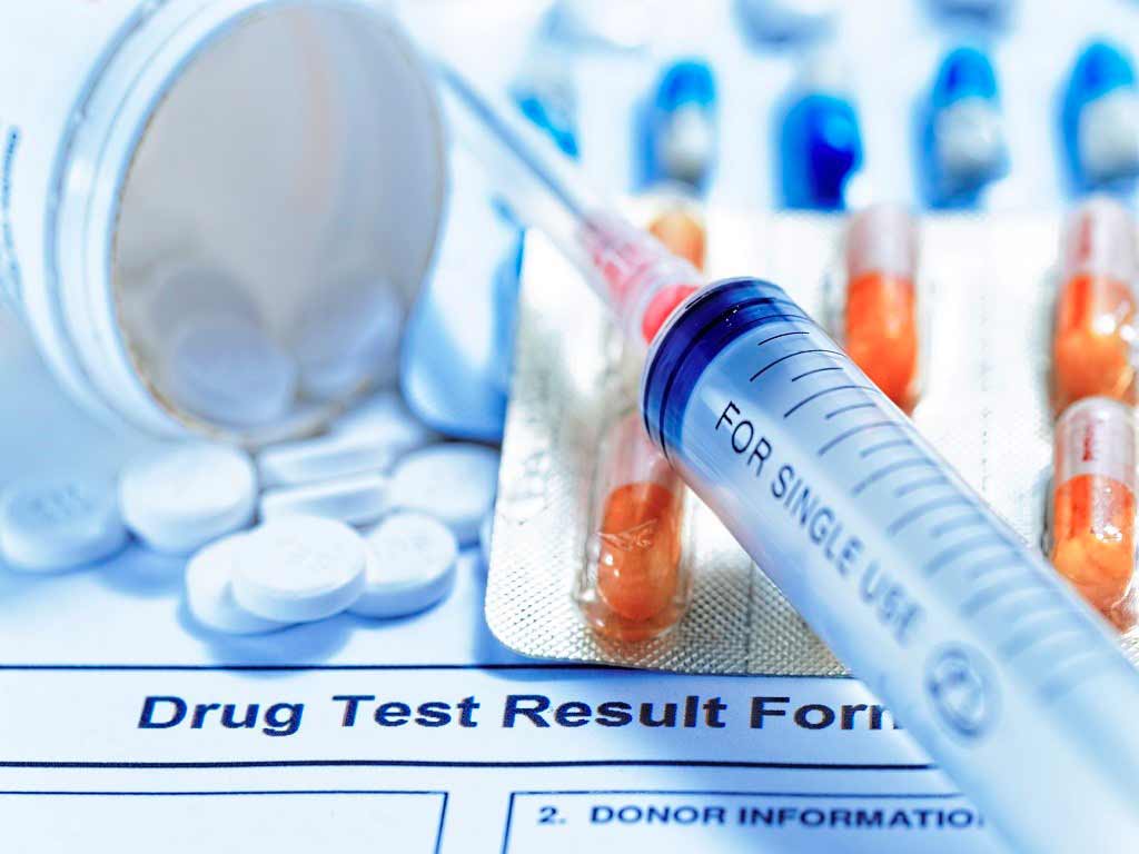 A drug test result form, pills, and syringe