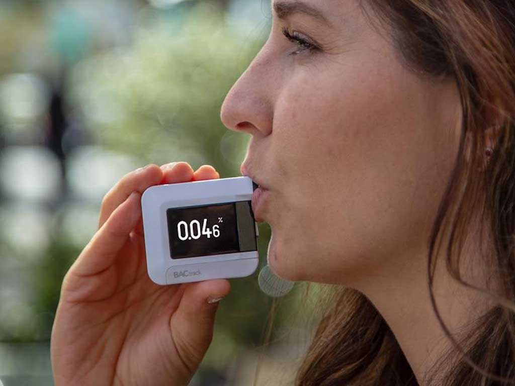 A woman blowing into a breathalyser.