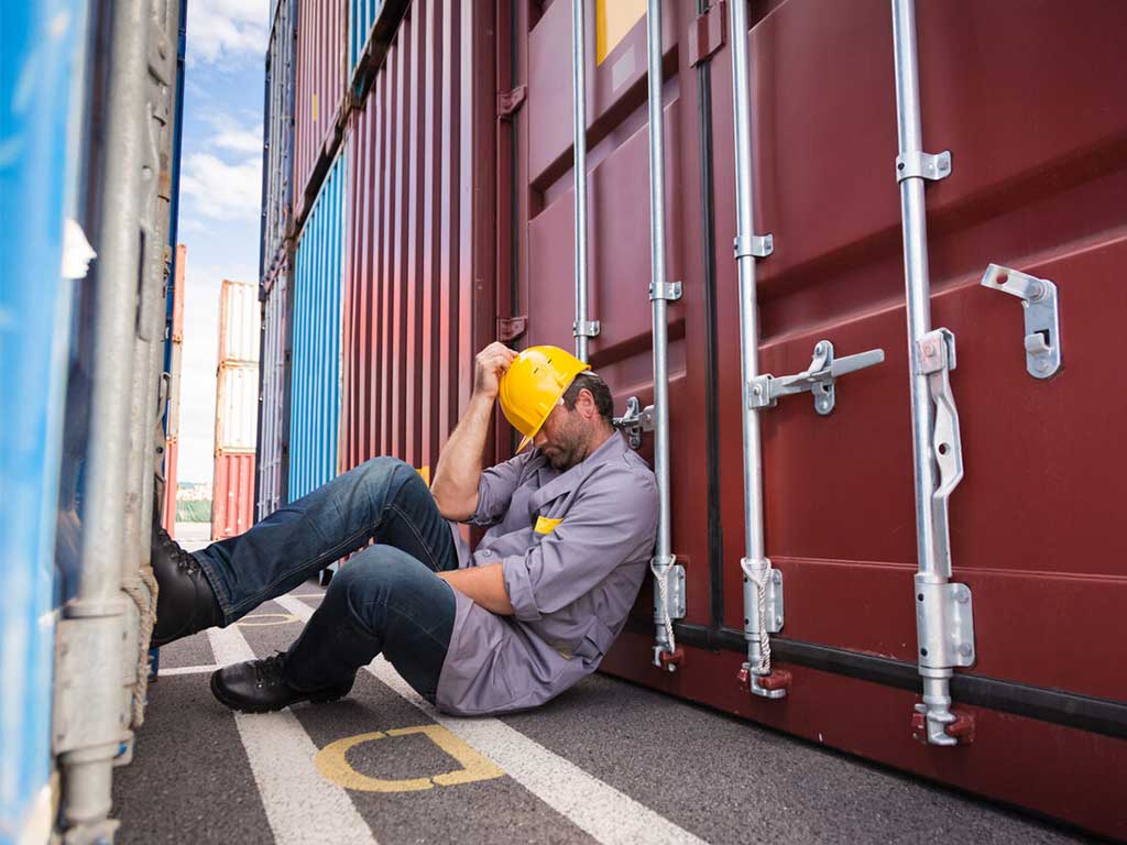 A worker sleeping behind a container van