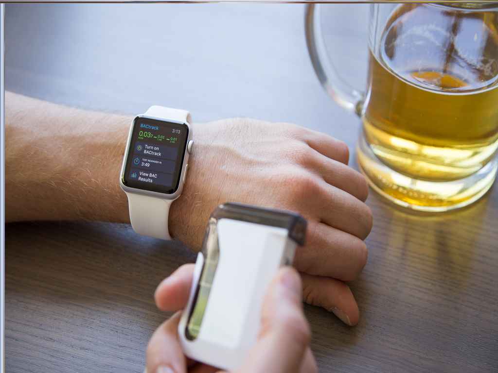 A person connecting a smartphone breathalyser to a smartwatch