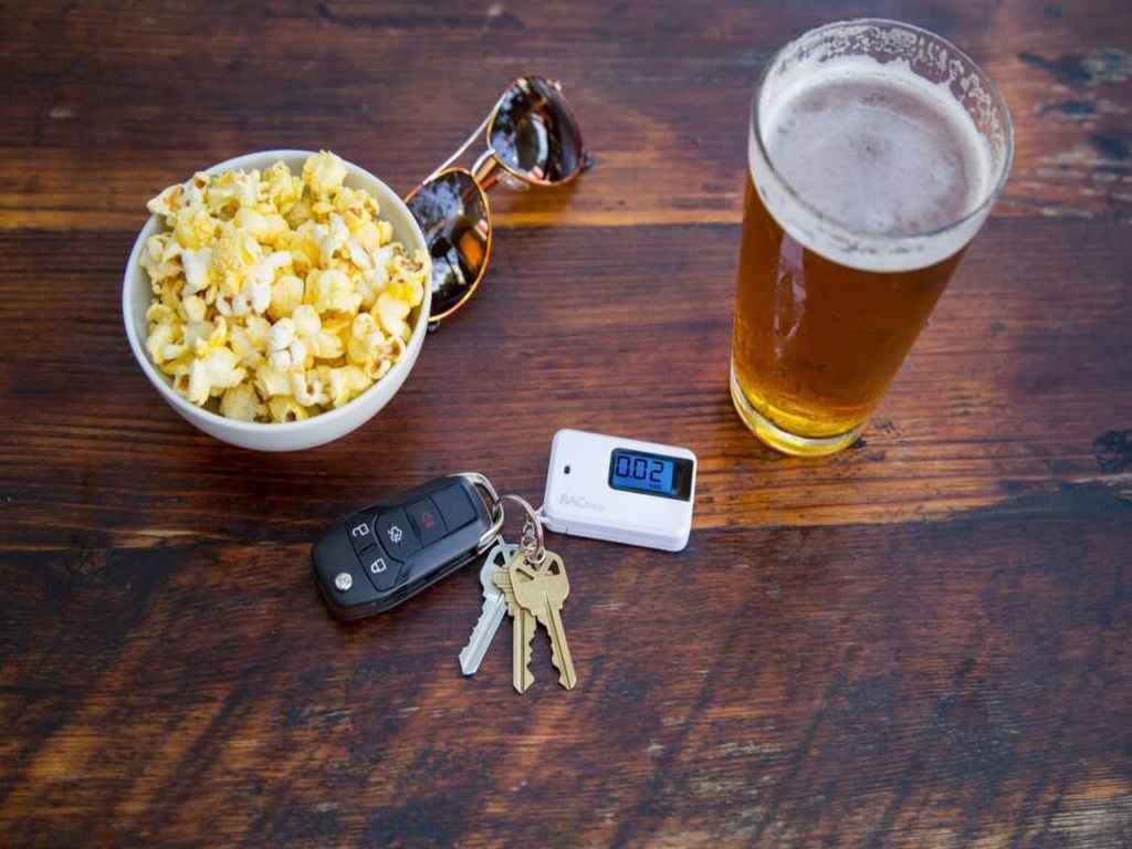On the table, there are popcorn, sunglasses, a glass of beer, and a breathalyser