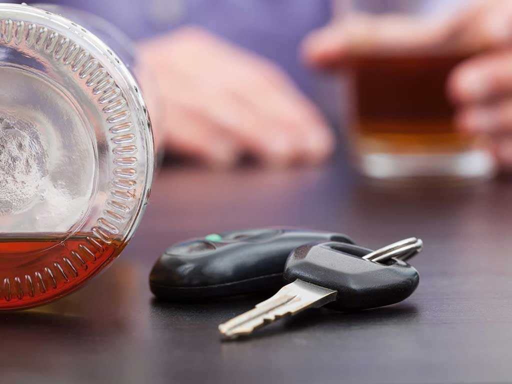 A car key in front of a person holding a glass of drink
