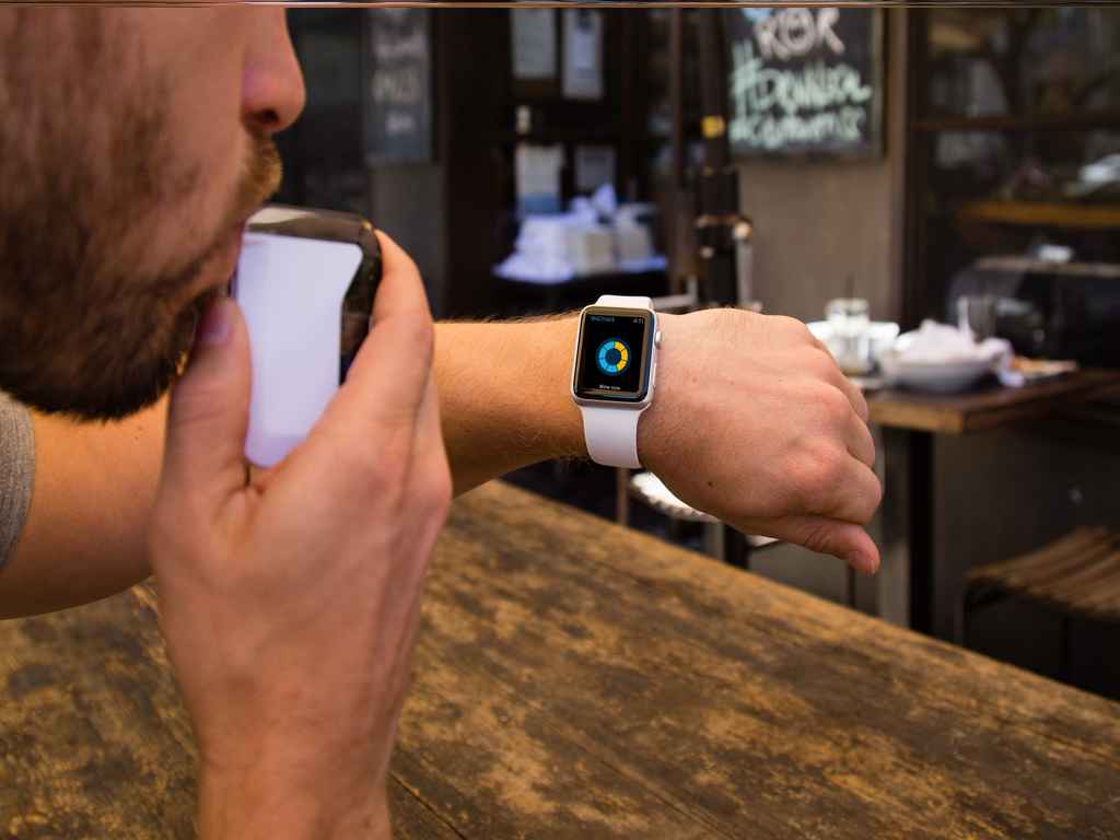 A person blowing to a breathalyser while looking at a smartwatch