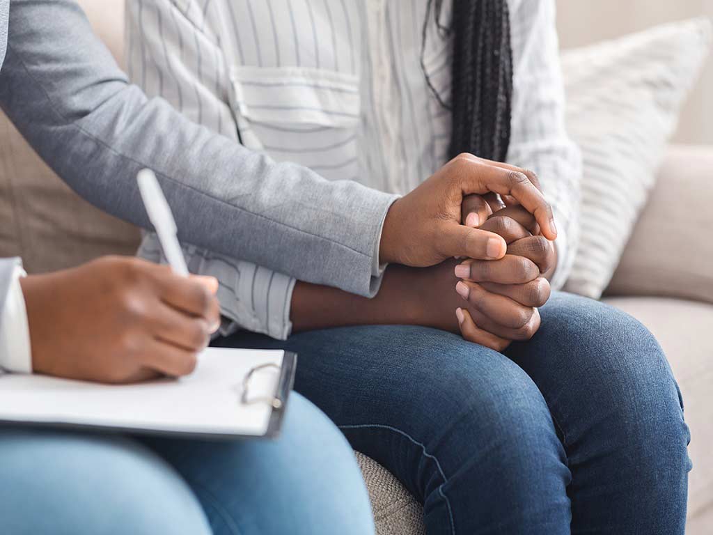 A therapist holding the hands of a patient during counselling