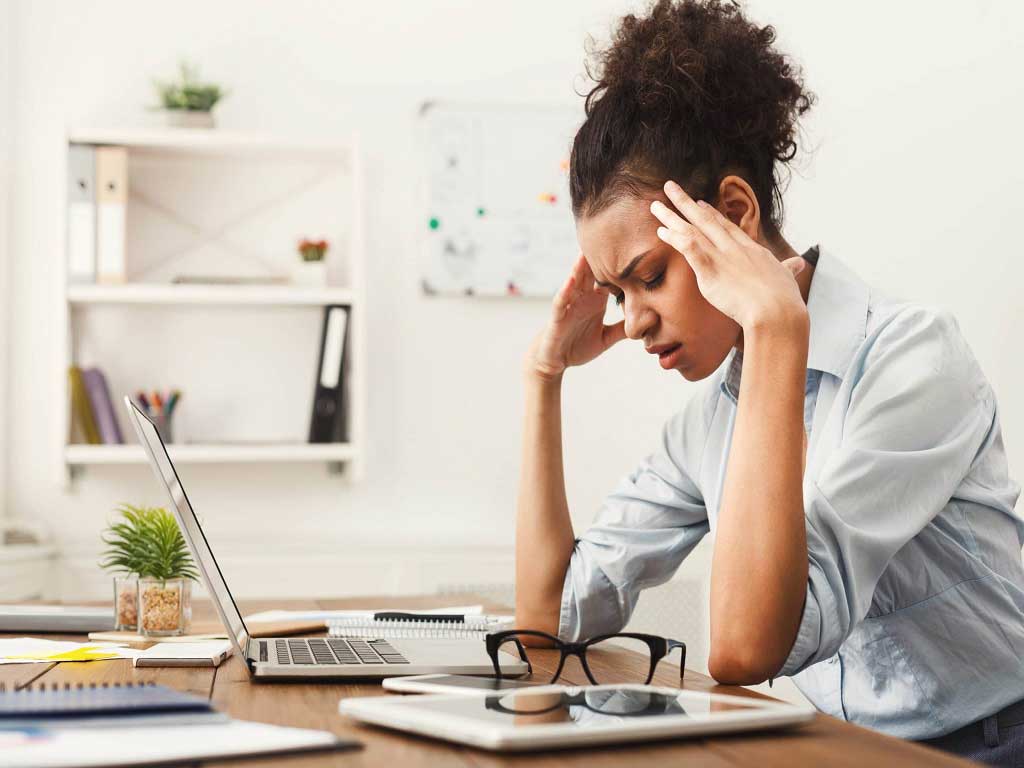 A woman at her desk touching her head area due to pain or discomfort