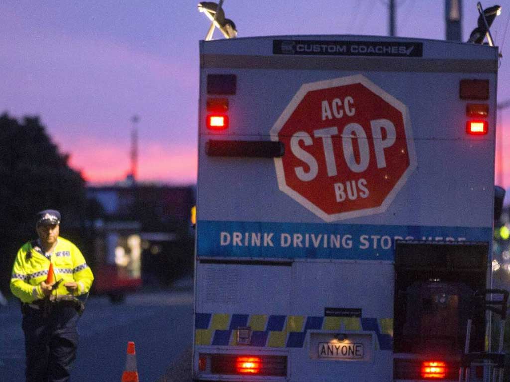 A police officer beside a mobile testing bus with a stop sign