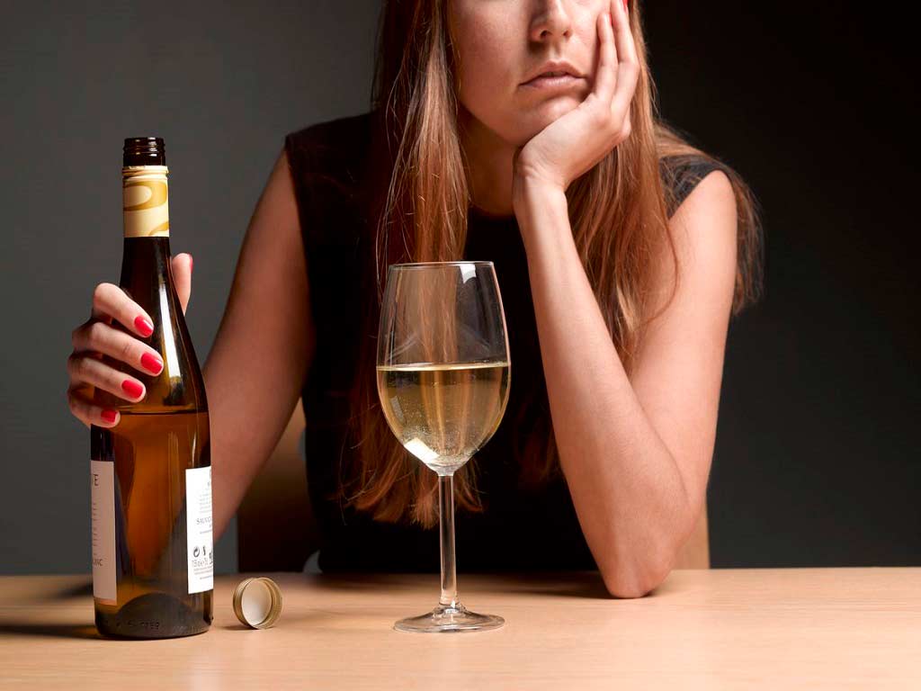 A woman with a bottle and glass of alcohol