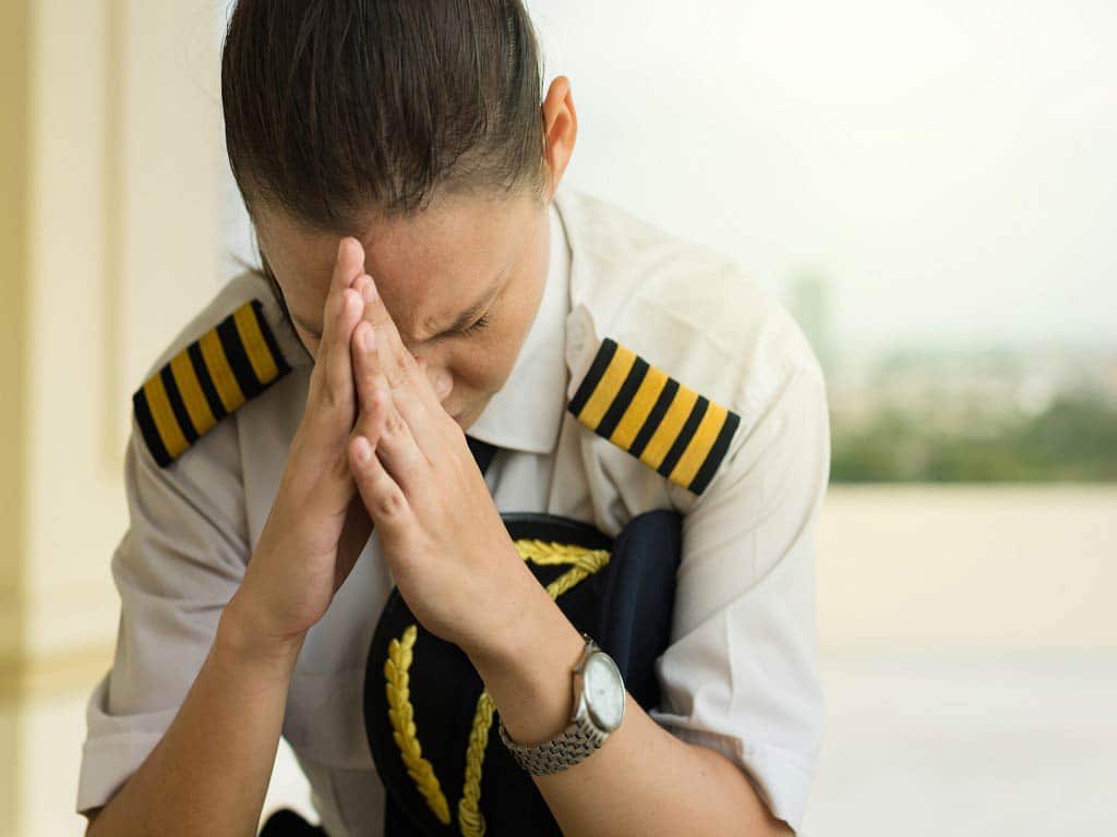An airline employee looking distressed at work