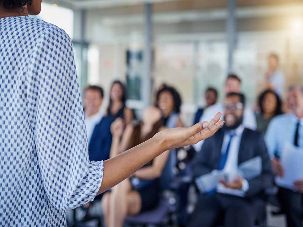 A female professional addressing an audience in a corporate environment