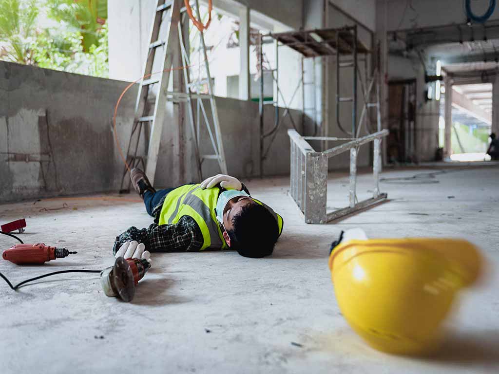 A worker lying on the ground after a workplace accident