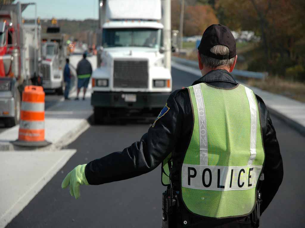 A police office stopping an incoming truck on the road