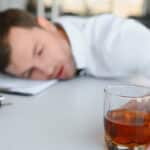 An intoxicated employee asleep while holding a glass of liquor