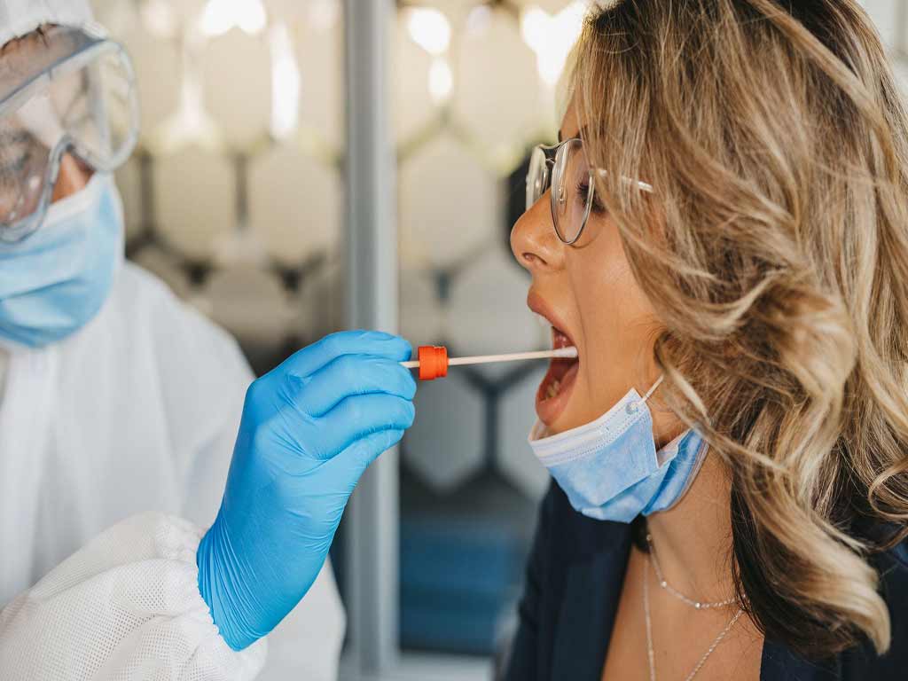 A professional collecting a saliva sample from a female patient