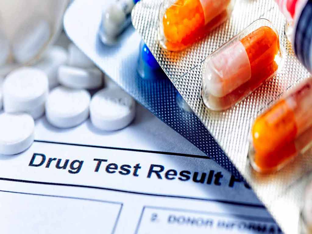 A drug test result and different types of drugs in the background
