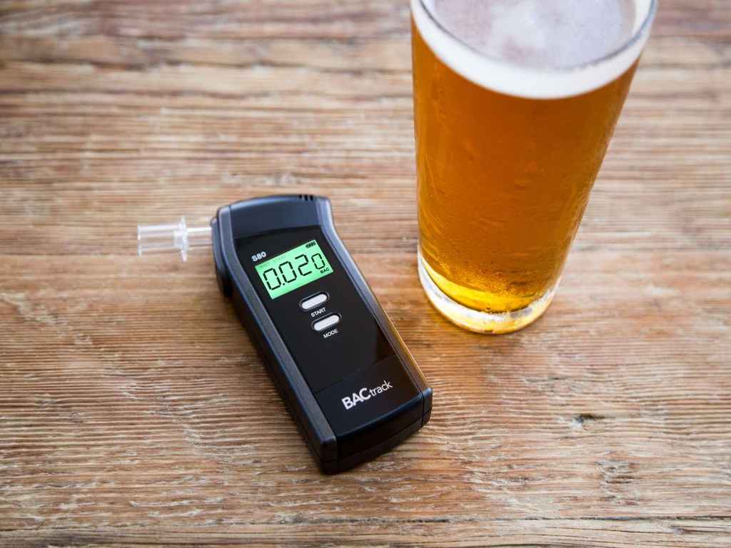 A breathalyser next to a glass of alcohol