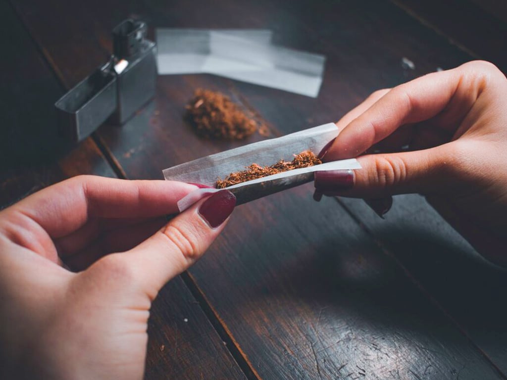 A person rolling up a paper with drugs