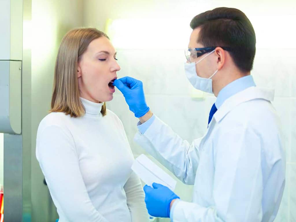 A professional collecting saliva samples from a female candidate