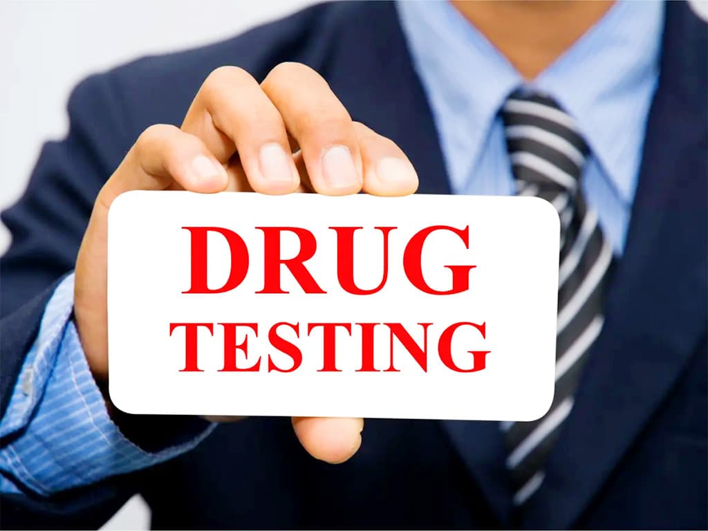 A person in corporate attire holding a "drug testing" sign