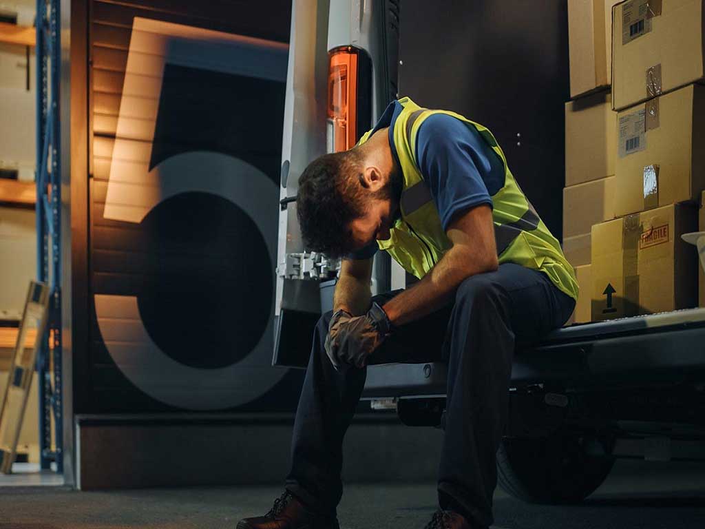 A stressed man with his head down outside of the work site
