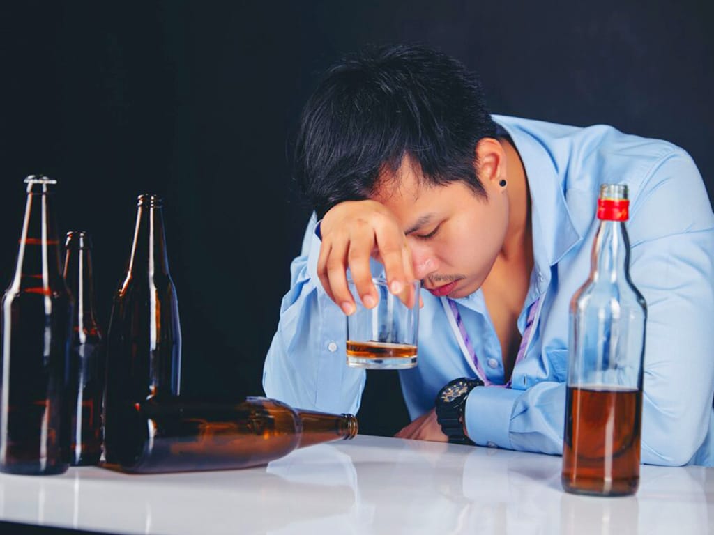 Man feeling tired while holding a glass of alcohol