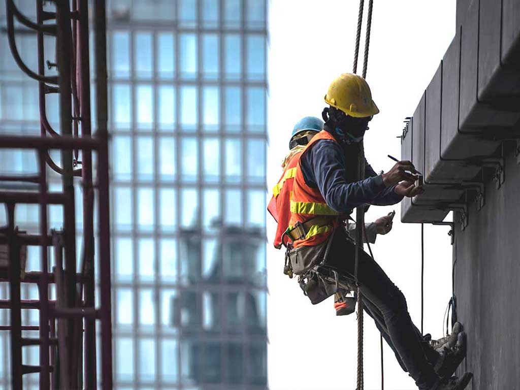 Two people in harness working outside a building