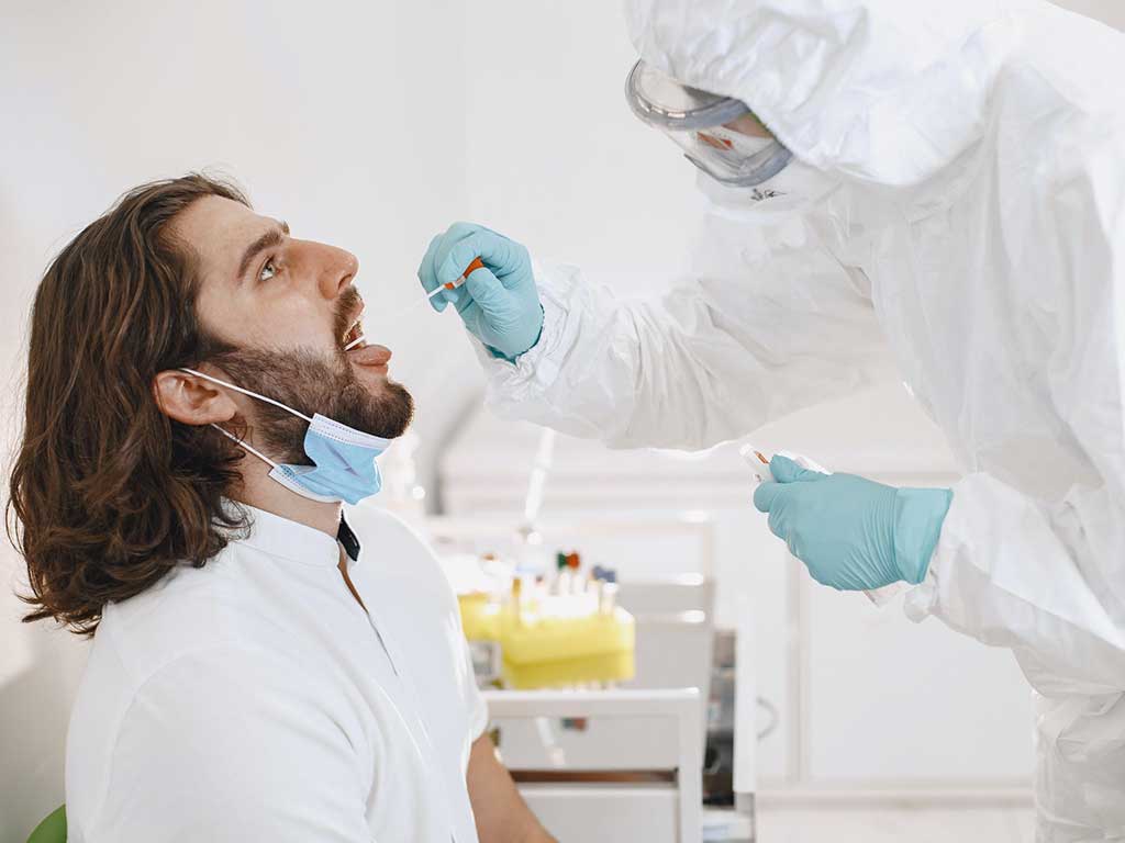 A lab professional getting a saliva sample from a male patient