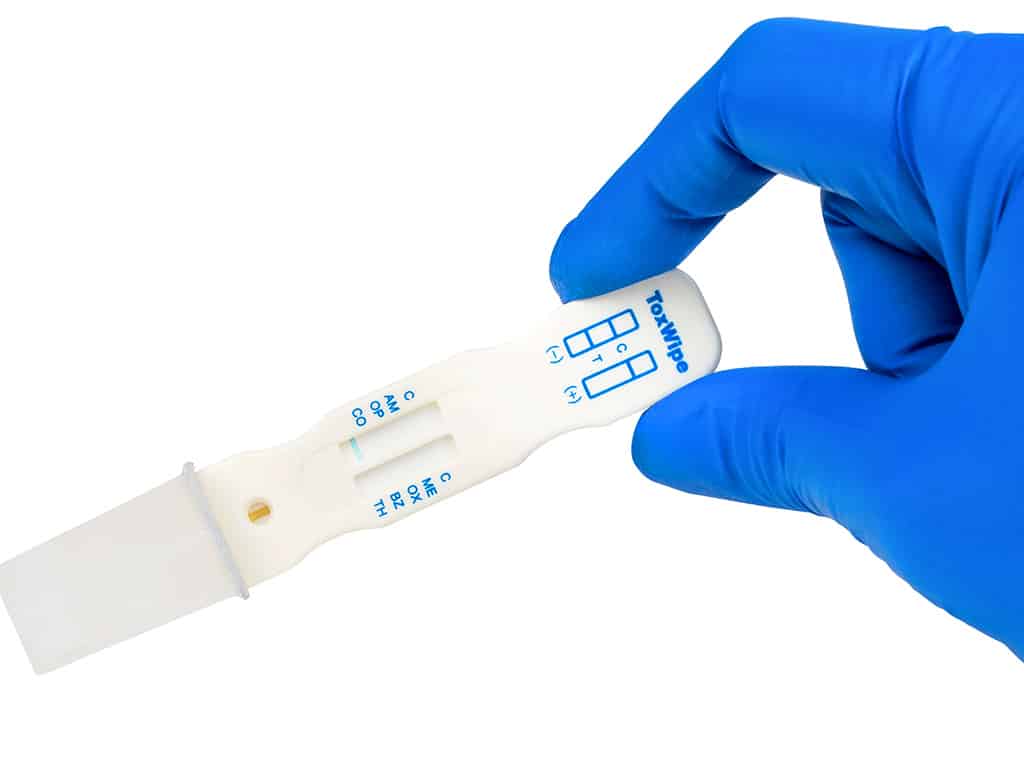 A gloved hand holding the Toxwipe 7 Saliva Drug Test Kit