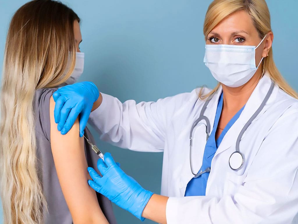 A medical professional inserting a needle in the arm of a female patient