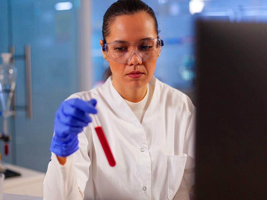 A female professional holding and testing a blood sample in a lab