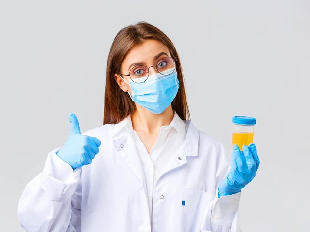 A friendly-looking laboratory personnel holding a sample of urine