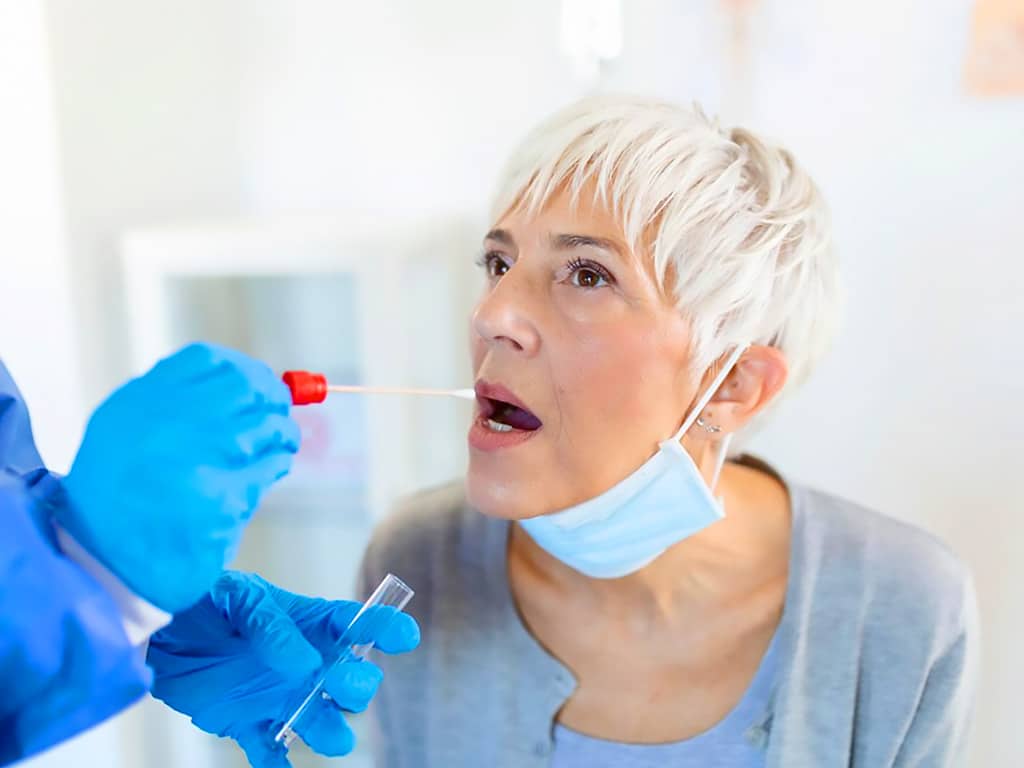 A mature woman getting a mouth swab test from a technician