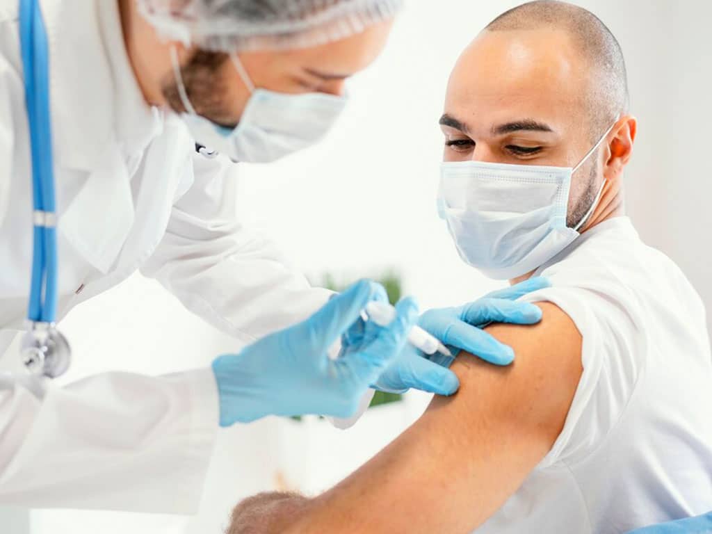 A lab technician inserting a needle to a patient to collect blood samples