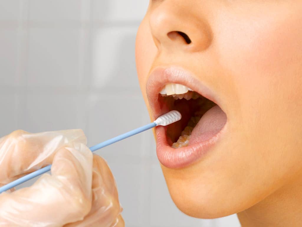 A personnel inserting a mouth swab inside a patient's mouth